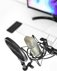 Podcast microphone on a desk beside a keyboard