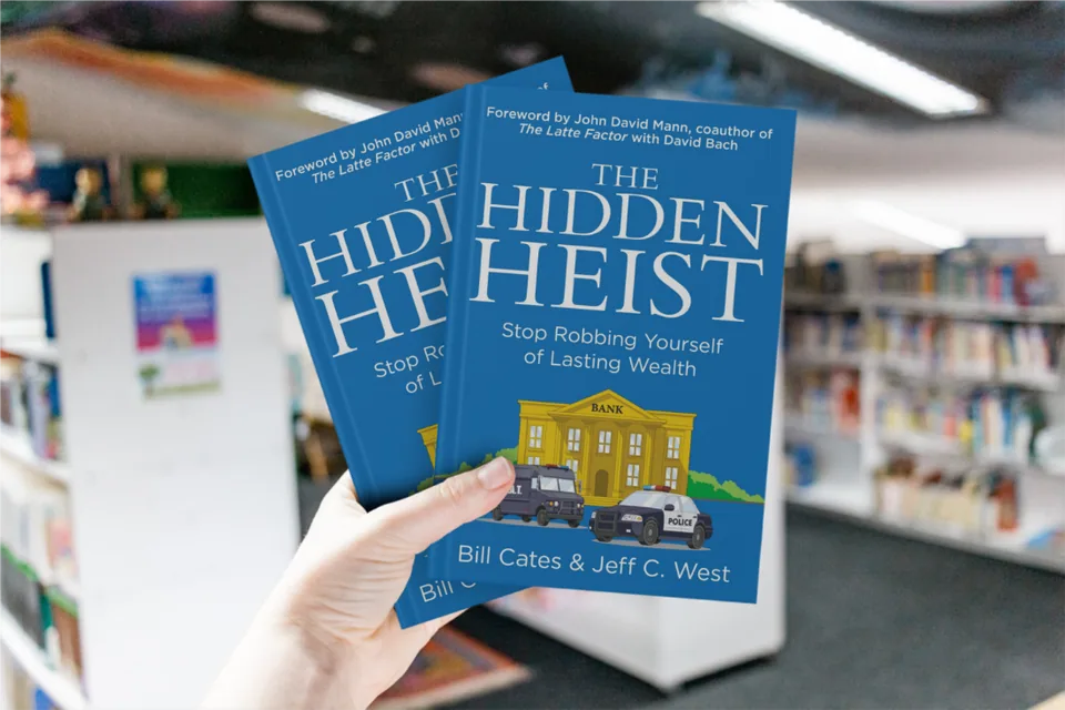 Hand holding two copies of The Hidden Heist in a bookstore